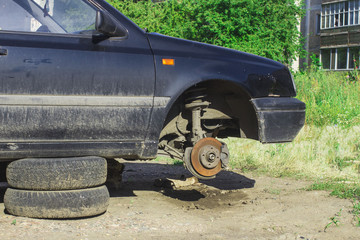car without a wheel, suspended on tires in the courtyard of a house