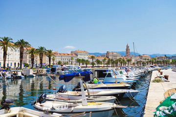 Fototapeta na wymiar Split old city with the Riva palm promenade and the Diocletian palace from the pier with fisher boats in the foreground in Croatia