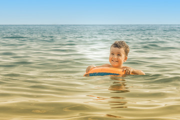 A happy child bathes in the sea on an inflatable circle