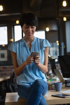 Female executive using mobile phone at desk in office