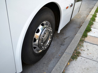 Chrome plated wheel of the white intercity bus on the street close-up