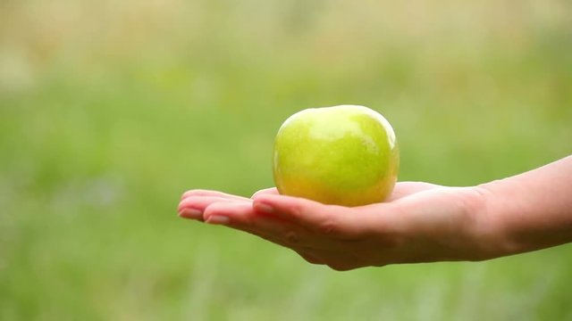 A man takes an Apple lying on a woman's hand. Exchange, kindness, care and love. The girl holds the Apple and gives it to the man.