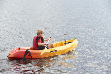 Active happy child. Teenage school boy having fun enjoying adventurous experience kayaking on the lake on a sunny day during summer vacation