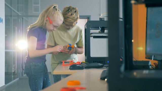 Kids working with 3D printer. Boy and girl working in a science laboratory with printing equipment.