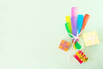 Bouquet of Many different multi-colored plastic hair combs, crest brushes and gift boxes isolated on light green pastel background. Mininmalistic hairdresser stylist concept. Copy space