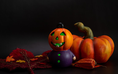 halloween autumn decoration with illuminated pumpkin head other artificial pumpkin and leaves orange colors on black background
