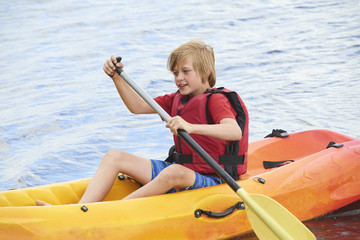 Obraz premium Active happy child. Teenage school boy having fun enjoying adventurous experience kayaking on the lake on a sunny day during summer vacation