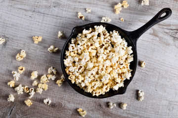  Prepared popcorn in frying pan, corn seeds in bowl and corncobs on kitchen table.Air salty popcorn. Salt popcorn on the wooden background . Chees .Popcorn texture