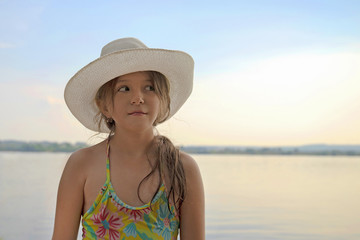 Fototapeta na wymiar portrait of a cute little girl in a white hat with a smile on her face in summer on the beach