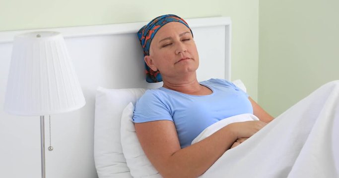 Portrait of a depressed cancer patient in hospital room laying on a bed and looking camera sadly
