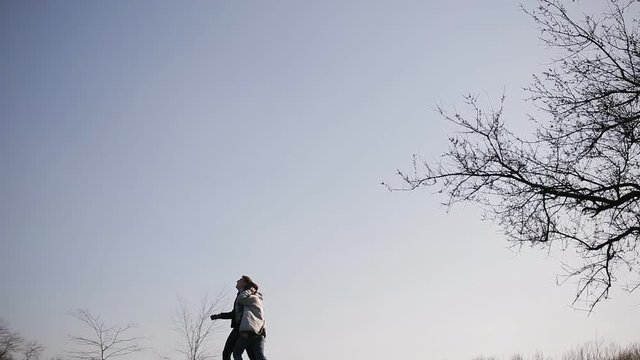 The silhouettes of the fleeing lovers on the hill near the big tree at sunset