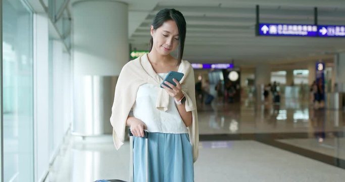 Woman use of mobile phone for checking flight number in the airport