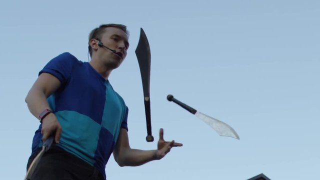Slow motion juggler with swords in city busker