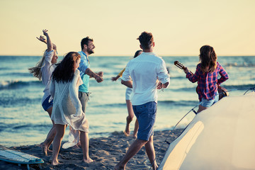Obraz premium Party on beach- young people dancing together at the beach on beautiful summer sunset.