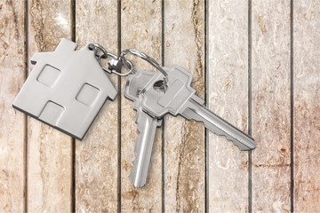 House keys with trinket on wooden background