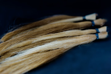 Close-up of hair cut for wig on a black bacground. Shaloow dept of field.