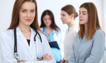Fototapeta premium Young beautiful female doctor smiling while consulting her patient. Physician at work. Medicine and healthcare concept