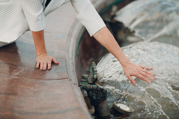 The girl touches the cool water in the fountain