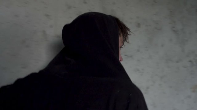 Young guy in a hood walks down the corridor