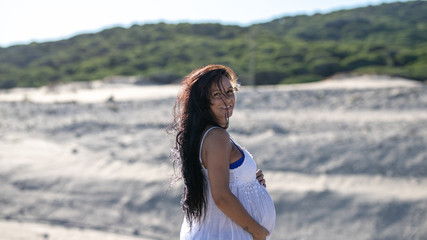 A pregnant model on the beach in summer. 