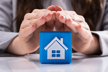 Woman Protecting Cubic Block With House Icon