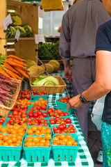 Obraz premium Variety of locally grown cherry tomatoes and carrots at Union Square Greenmarket Farmer's Market NYC with shoppers