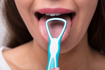Woman Cleaning Her Tongue With Cleaner - obrazy, fototapety, plakaty
