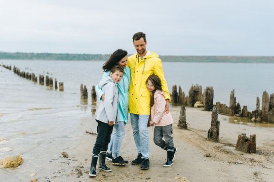 Beautiful family portrait dressed in colorful raincoat near the lake
