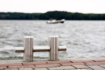 Bollard with a mooring line wrapped around it. Moored boats at the yacht harbor.