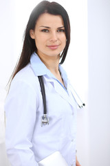 Brunette female doctor standing straight at hospital. Medicine and health care concept