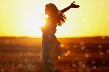 Young woman on field under sunset light