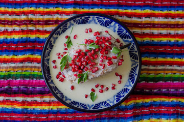 Chile en nogada en plato de talavera poblana en fondo colorido o reboso de colores mexicanos