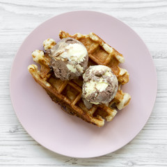 Traditional belgian waffle with icecream on pink plate over white wooden background, top view. Closeup.