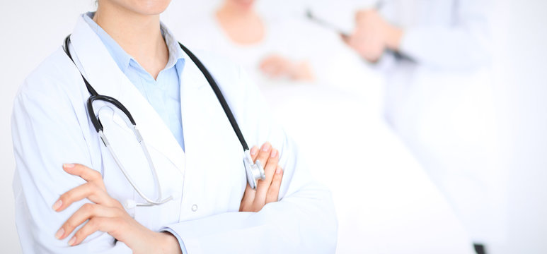 Unknown female doctor with medical staff  at hospital. Closeup of stethoscope