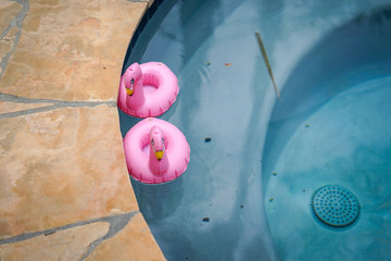 Two small flamingo floats in a swimming pool