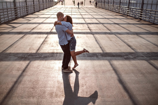 Young And Beautiful Couple Kissing On The Street On The Light And Shadows Of Building.