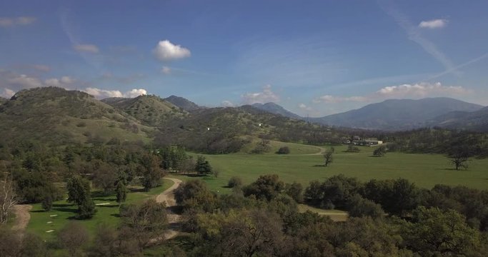drone shot/ helicopter shot of a green field in the mountains.