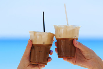 Cheers, ice cold coffee on the beach with straws, in summer