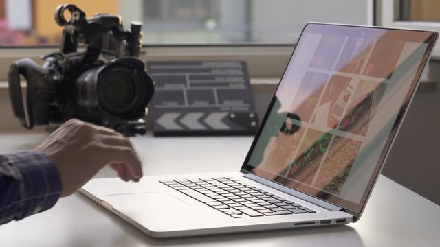 A cameraman browse  photo in social network and then power off a notebook. Documentary camera and Clapperboard in background