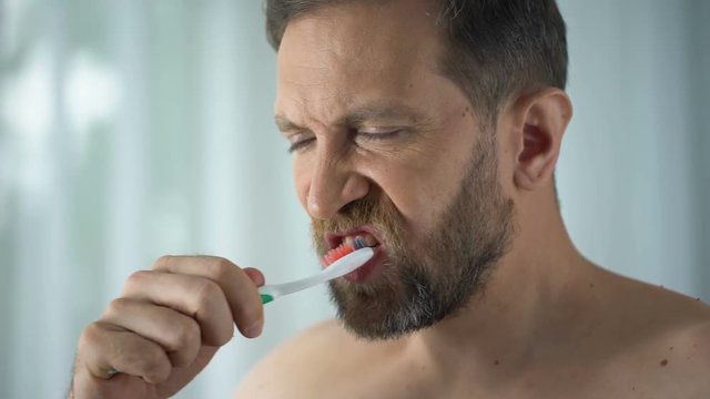 Male in bathroom looking at blood toothbrush, oral hygiene, parodontosis illness