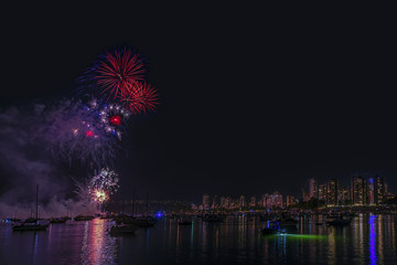 flashes of night fireworks over the ocean with floating yachts and ships