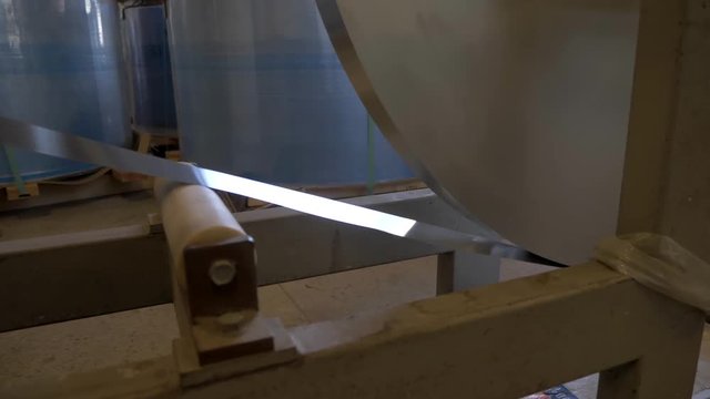 A slow-motion video of unrolling aluminum coil.