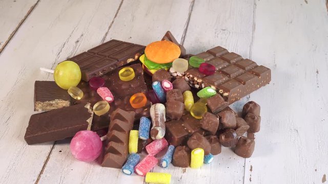 Chocolate bars and candies on the table. Dark chocolate heap, close up shot.