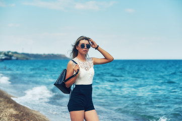 Attractive girl on the sea coast . Young stylish woman on a walk by the sea