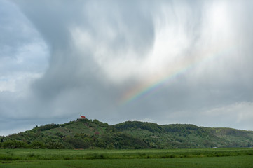 Obraz na płótnie Canvas Kirche auf Hügelkette vor Regenbogen und Sturmwolken