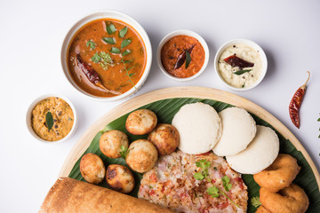 Group of South Indian food like Masala Dosa, Uttapam, Idli/idly, Wada/vada, sambar, appam, semolina halwa, upma served over banana leaf with colourful chutneys, selective focus