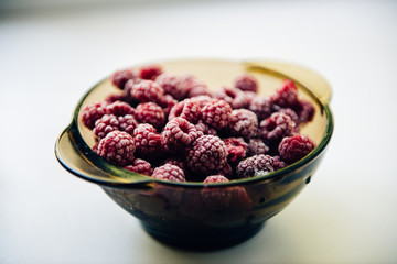 Frozen raspberries on a plate on white background lifestyle