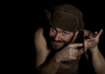 frightening bearded man showing middle finger. strange Russian man with a naked torso and a woolen hat. free space for your text