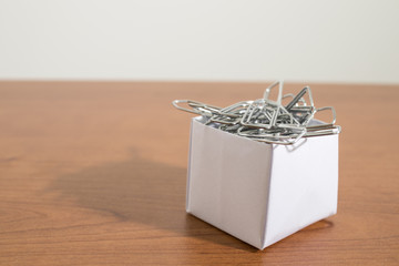 Paper box full of clasps on a wood table