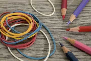 Colored pencils and rubber bands on a wood table